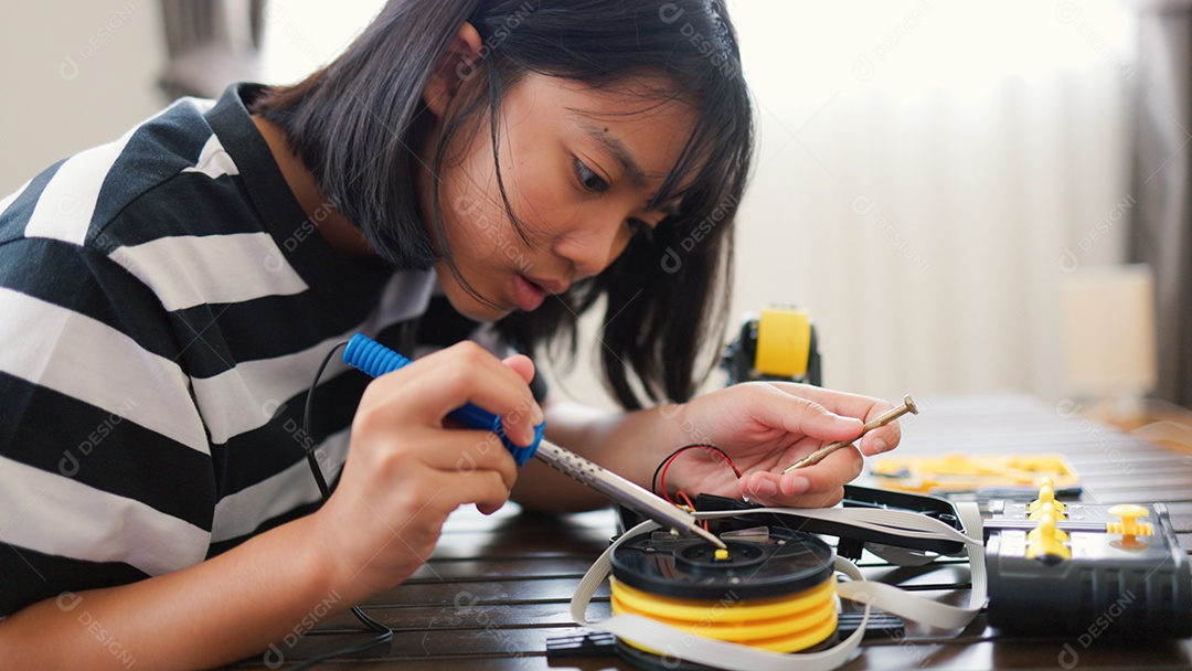 Garota asiática montando peças de robô em casa
