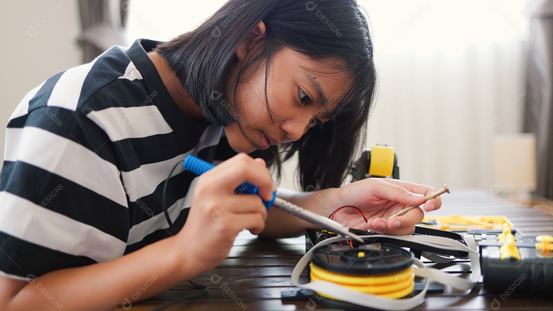 Garota asiática montando peças de robô em casa