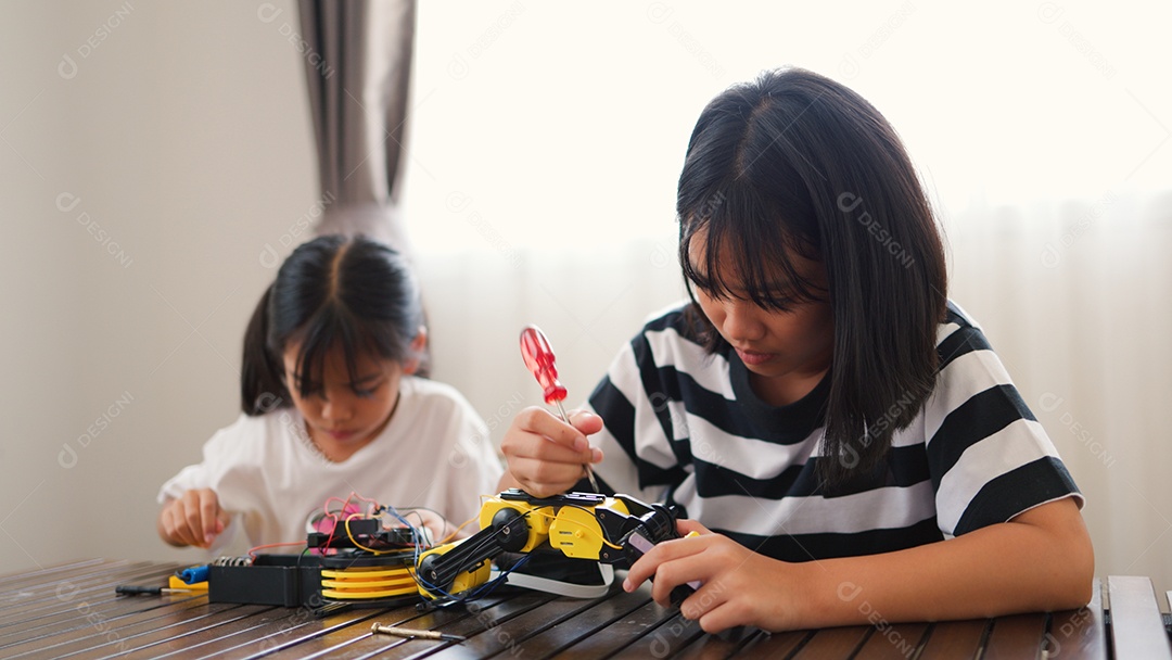 Garotas asiáticas montando peças de robô em casa