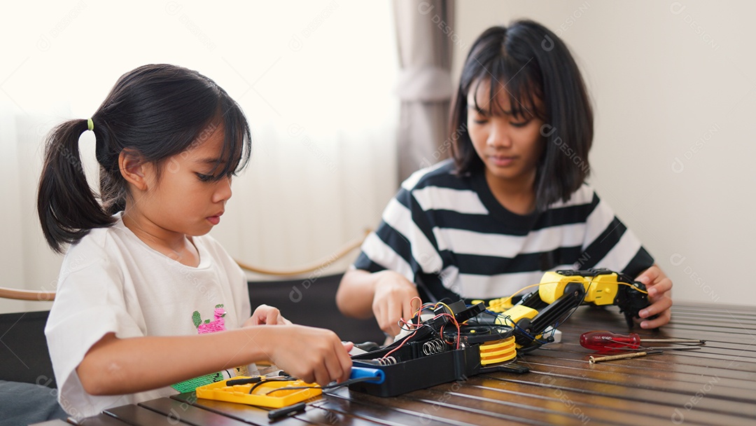 Garotas asiáticas montando peças de robô em casa