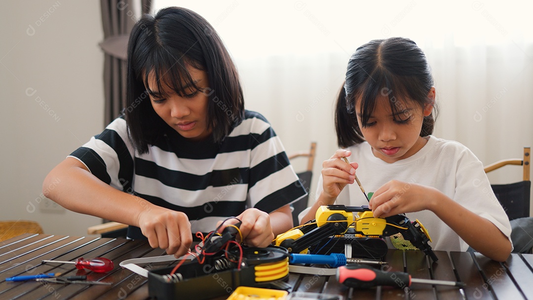 Garotas asiáticas montando peças de robô em casa