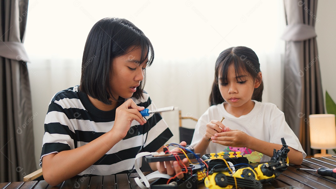Garotas asiáticas montando peças de robô em casa