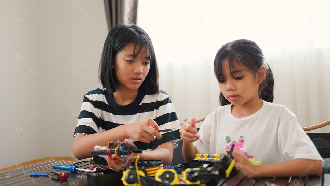 Garotas asiáticas montando peças de robô em casa