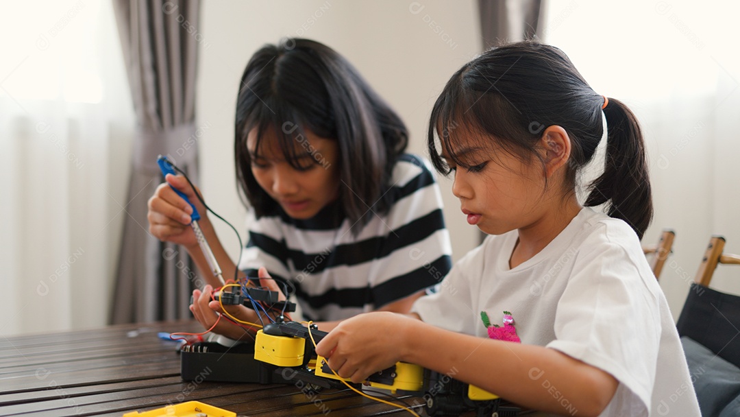Garotas asiáticas montando peças de robô em casa