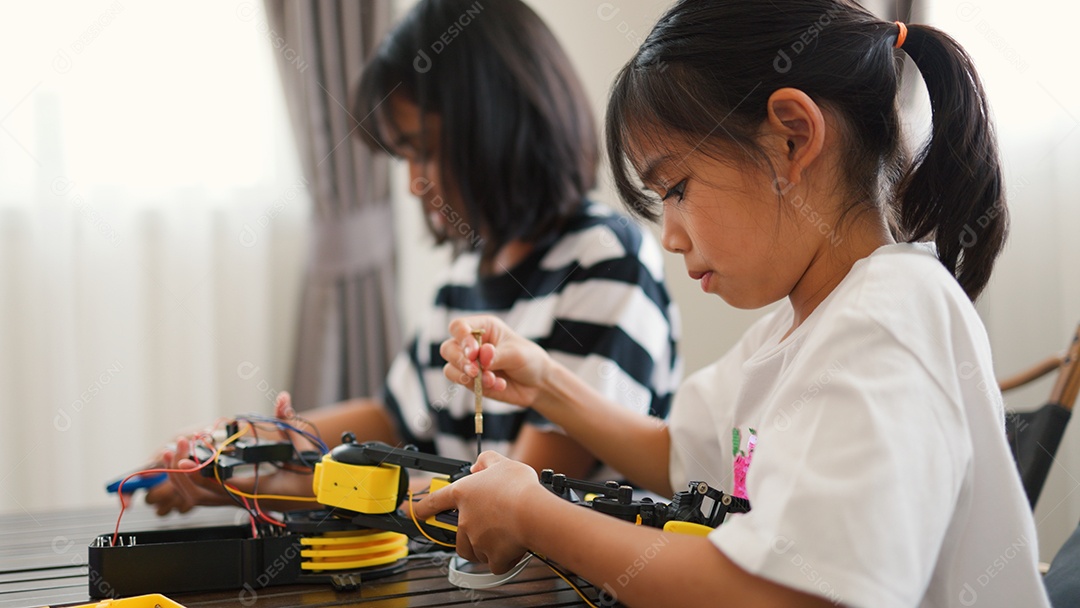 Garotas asiáticas montando peças de robô em casa