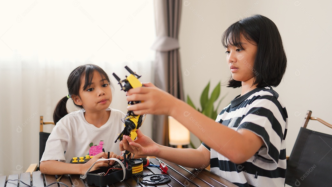 Garotas asiáticas montando peças de robô em casa