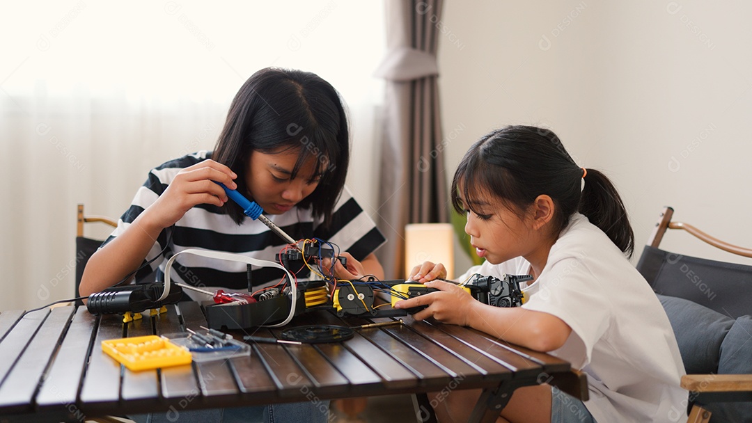 Garotas asiáticas montando peças de robô em casa