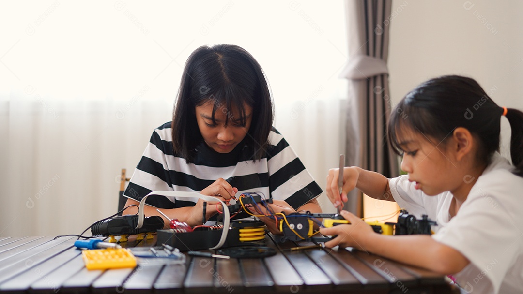 Garotas asiáticas montando peças de robô em casa