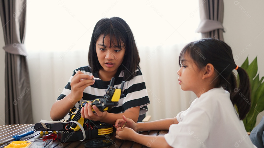 Garotas asiáticas montando peças de robô em casa