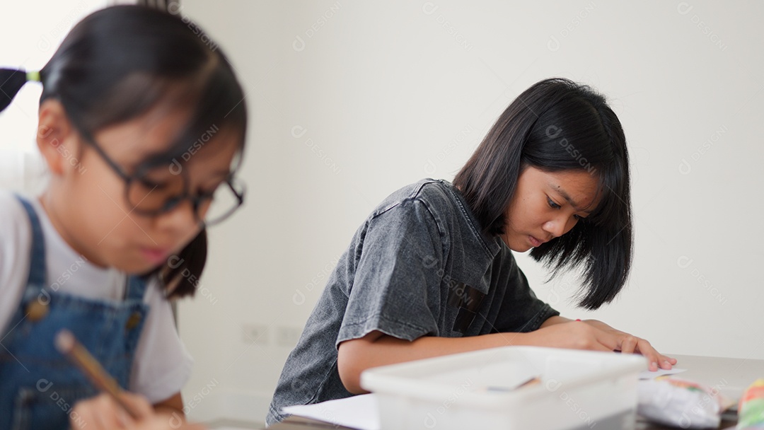 Duas meninas asiáticas estudando e desenhando em uma sala iluminada