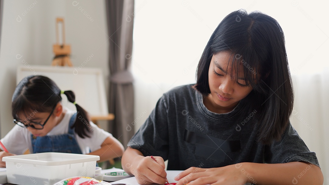 Duas meninas asiáticas estudando e desenhando em uma sala iluminada