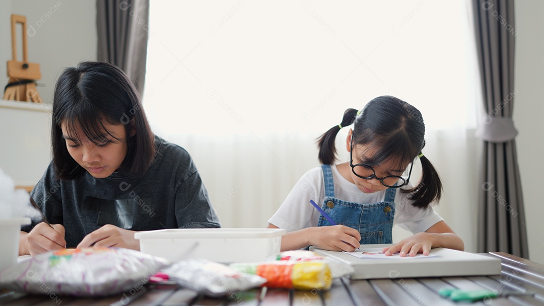 Duas meninas asiáticas estudando e desenhando em uma sala iluminada