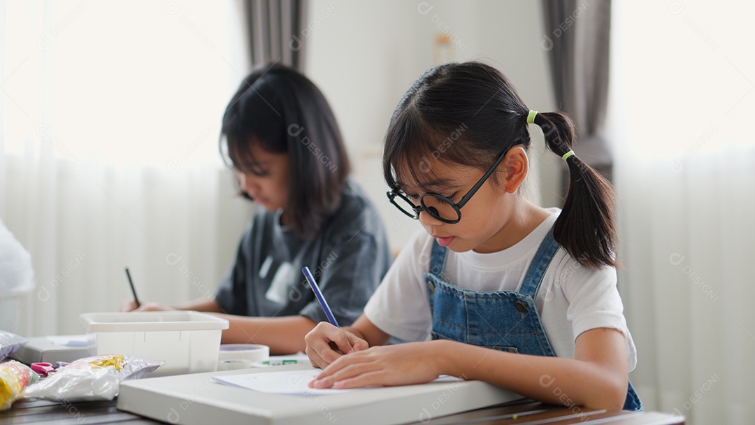 Duas meninas asiáticas estudando e desenhando em uma sala iluminada