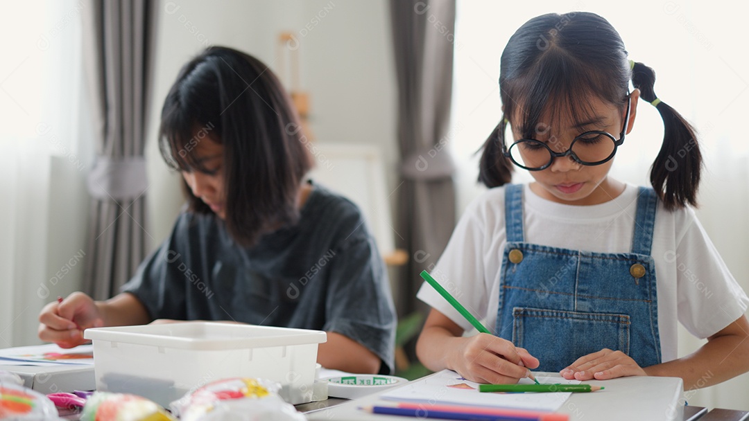 Duas meninas asiáticas estudando e desenhando em uma sala iluminada