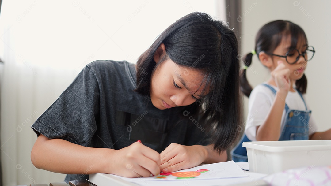 Duas meninas asiáticas estudando e desenhando em uma sala iluminada