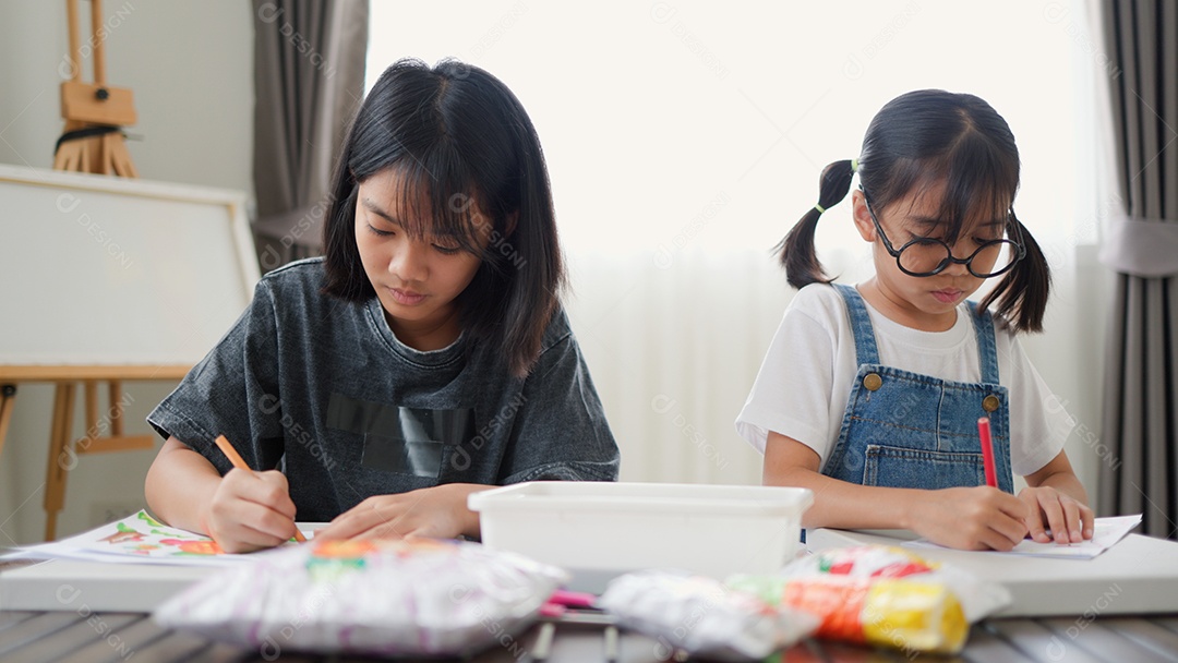 Duas meninas asiáticas estudando e desenhando em uma sala iluminada