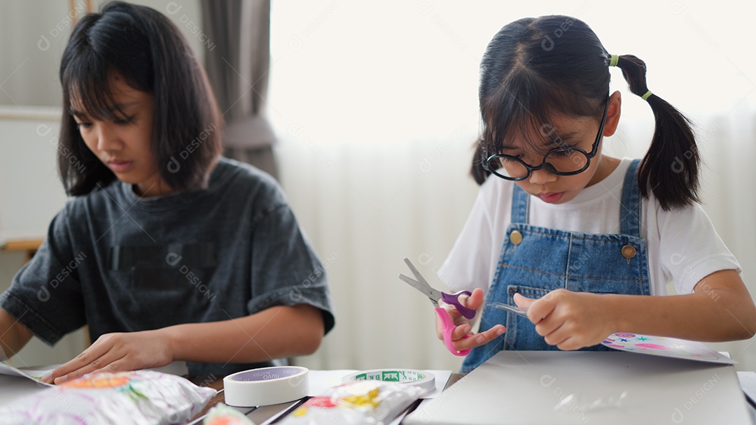 Duas meninas asiáticas estudando e desenhando em uma sala iluminada