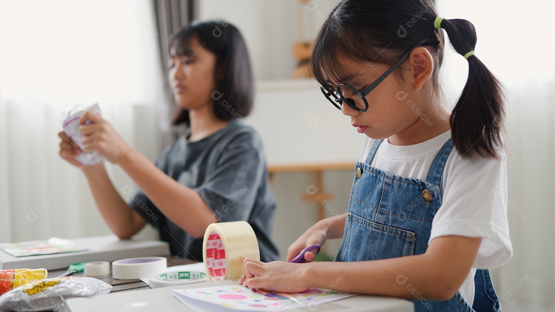 Duas meninas asiáticas estudando e desenhando em uma sala iluminada