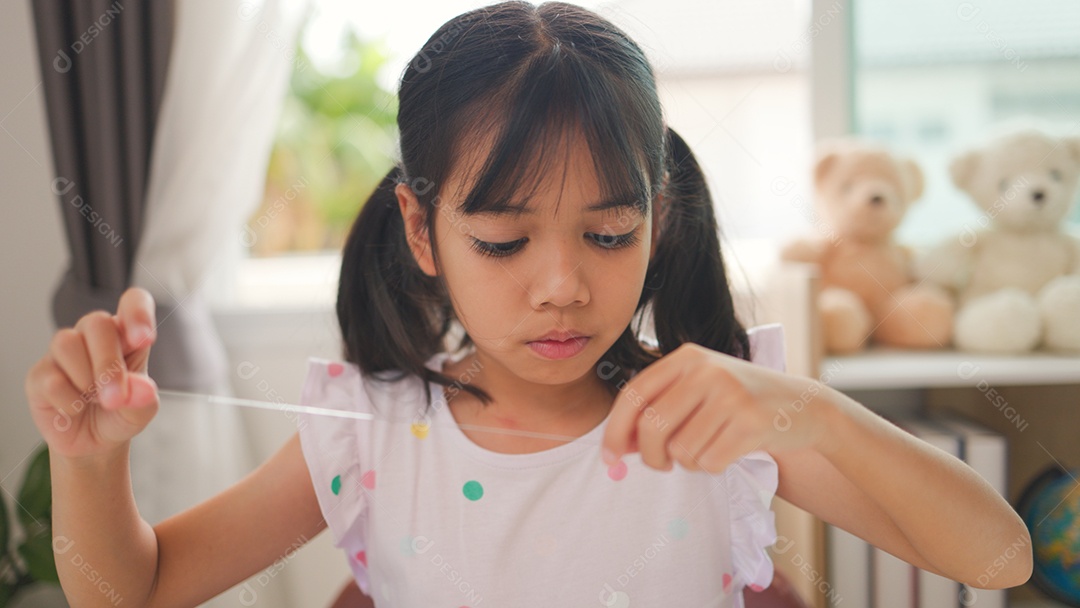 Garota asiática enfiando contas coloridas em casa