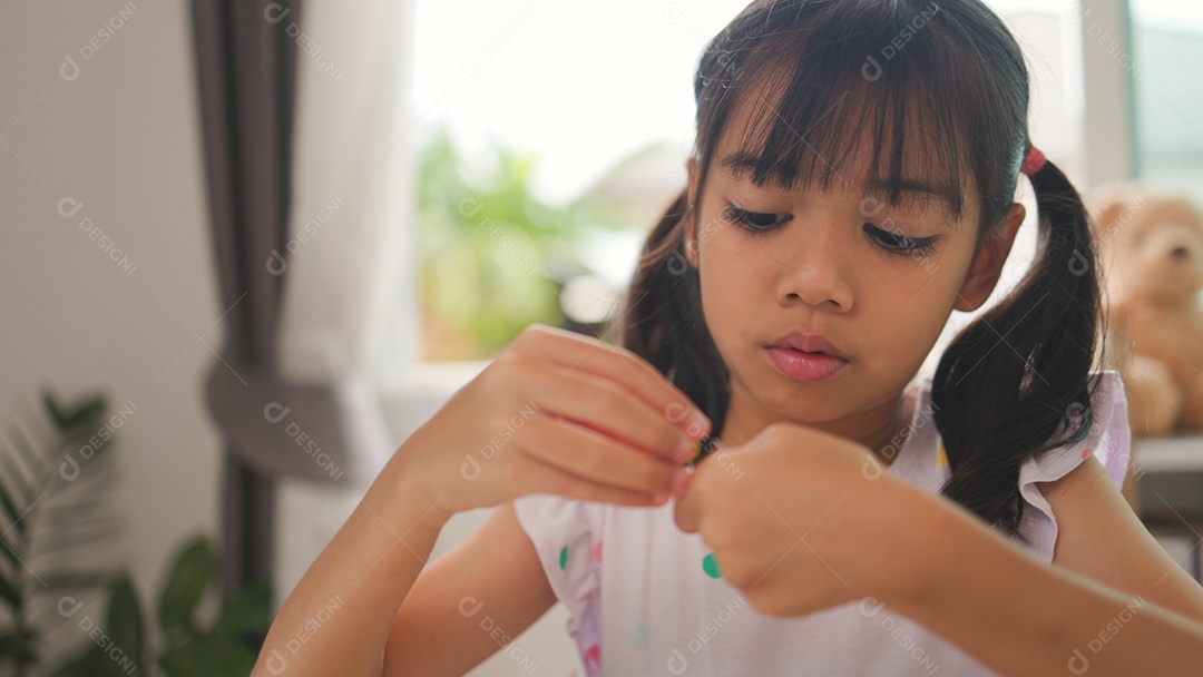 Garota asiática enfiando contas coloridas em casa
