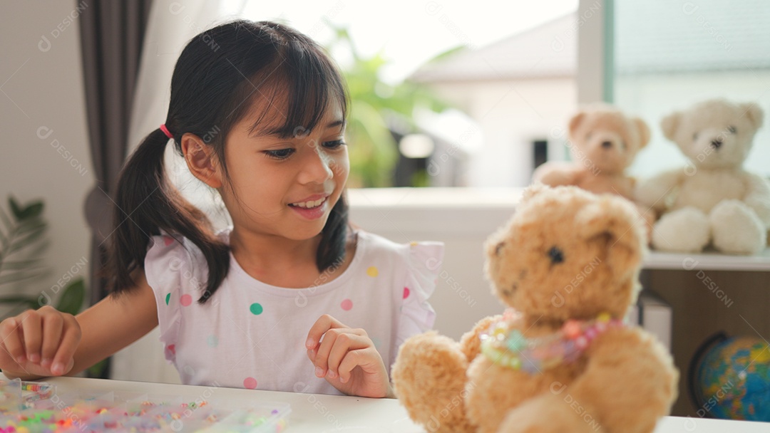 Garota asiática enfiando contas coloridas em casa