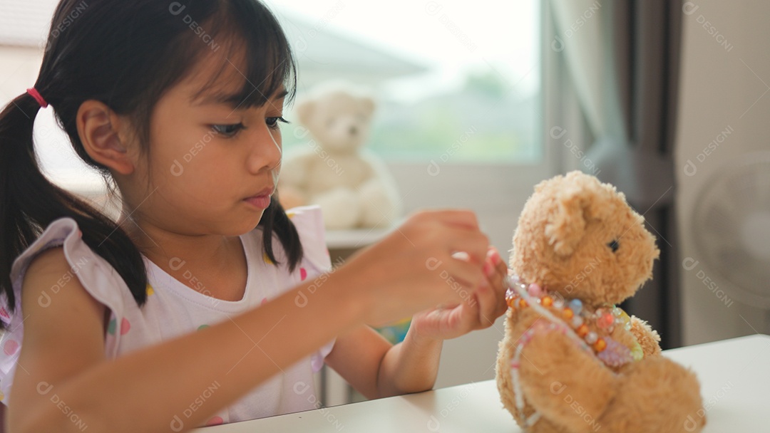 Garota asiática enfiando contas coloridas em casa