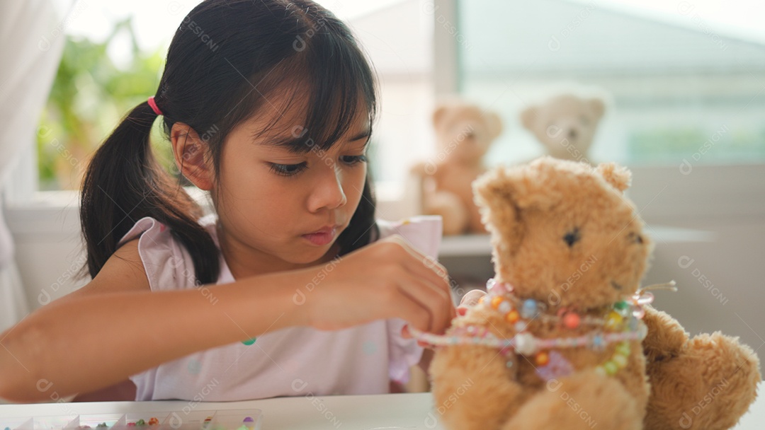 Garota asiática enfiando contas coloridas em casa