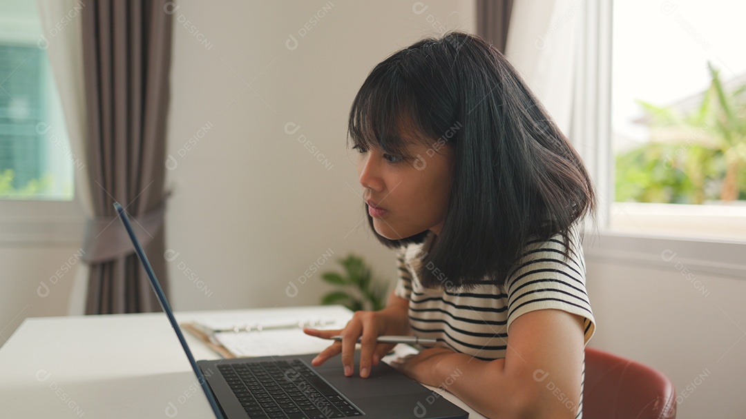Menina asiática estudando em casa com foco