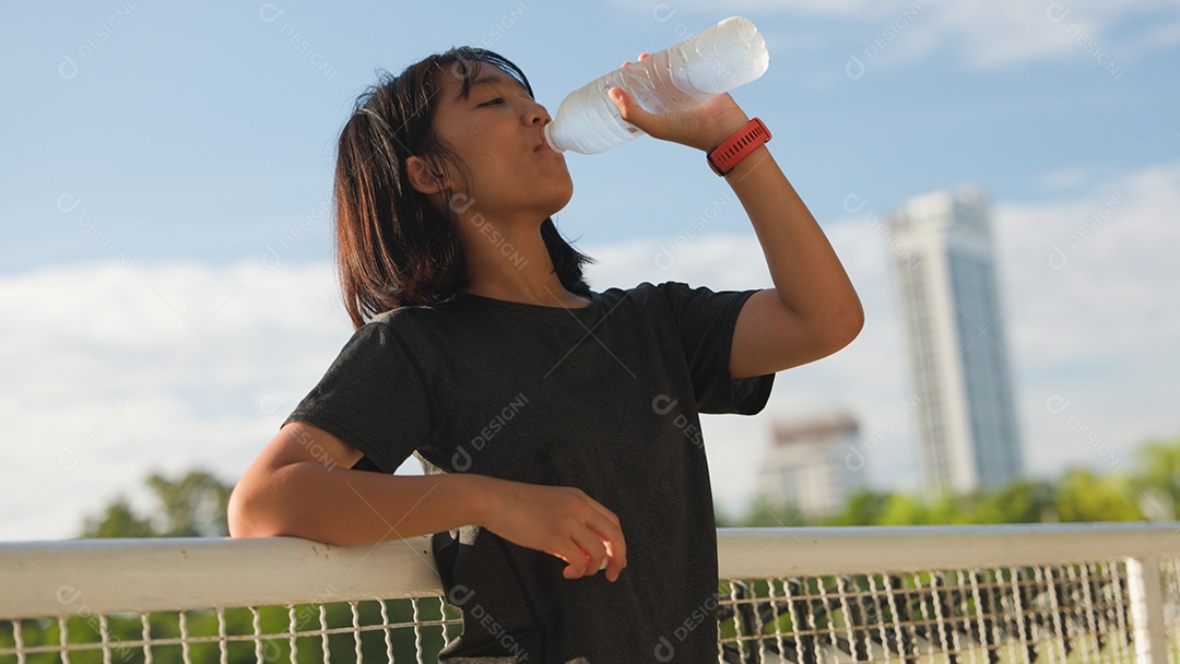 Adolescente asiática tomando água ao ar livre