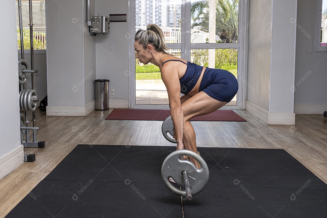 Mulher brasileira de 46 anos fazendo rosca direta com halteres
