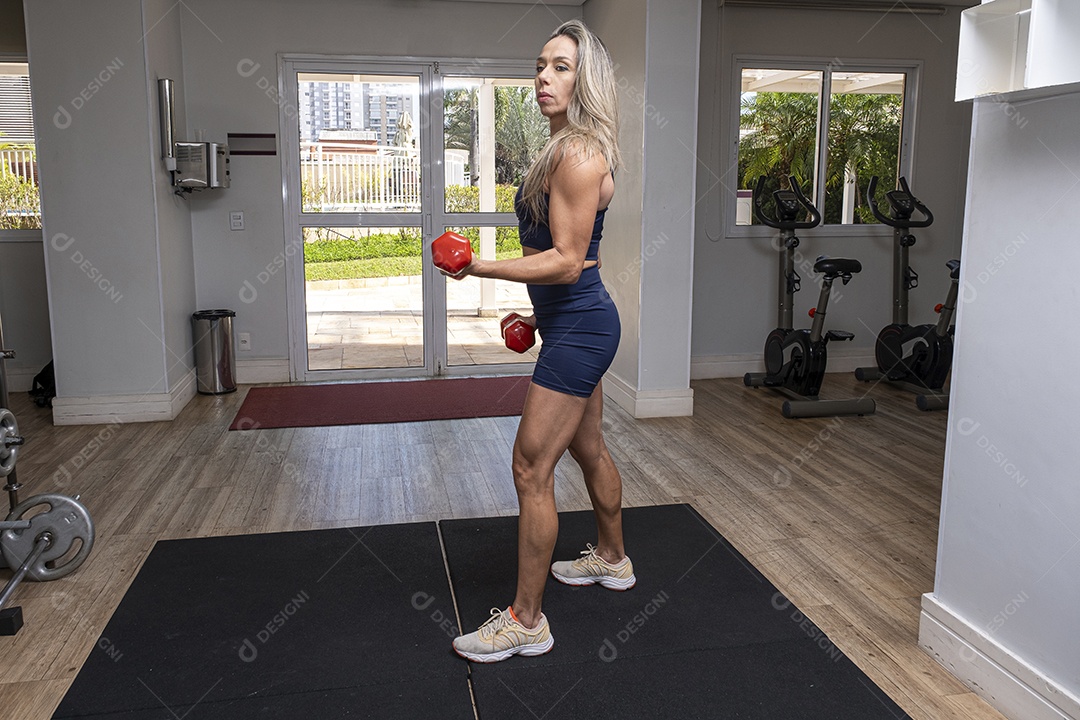 Mulher brasileira de 46 anos fazendo rosca direta com halteres