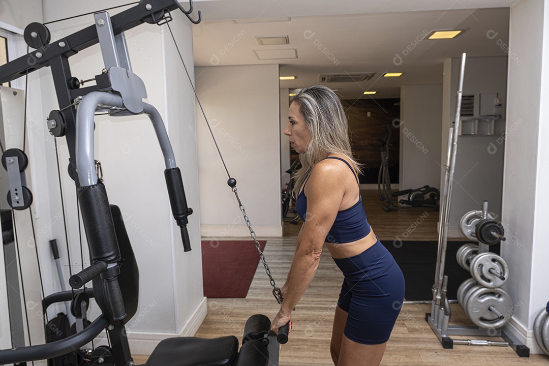 Mulher brasileira de 46 anos fazendo rosca direta com halteres