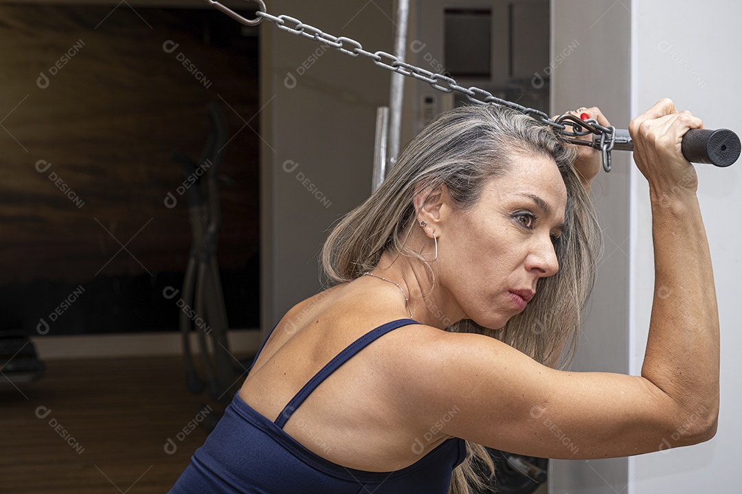 Mulher brasileira de 46 anos fazendo agachamento com halteres