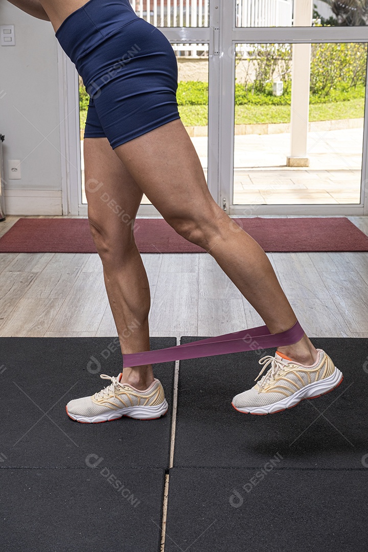 Pernas de uma mulher fazendo exercício com faixa elástica