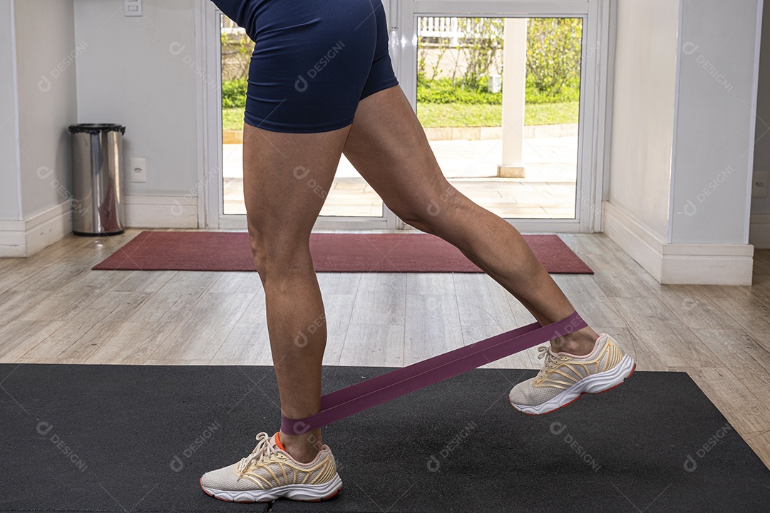 Pernas de uma mulher fazendo exercício com faixa elástica