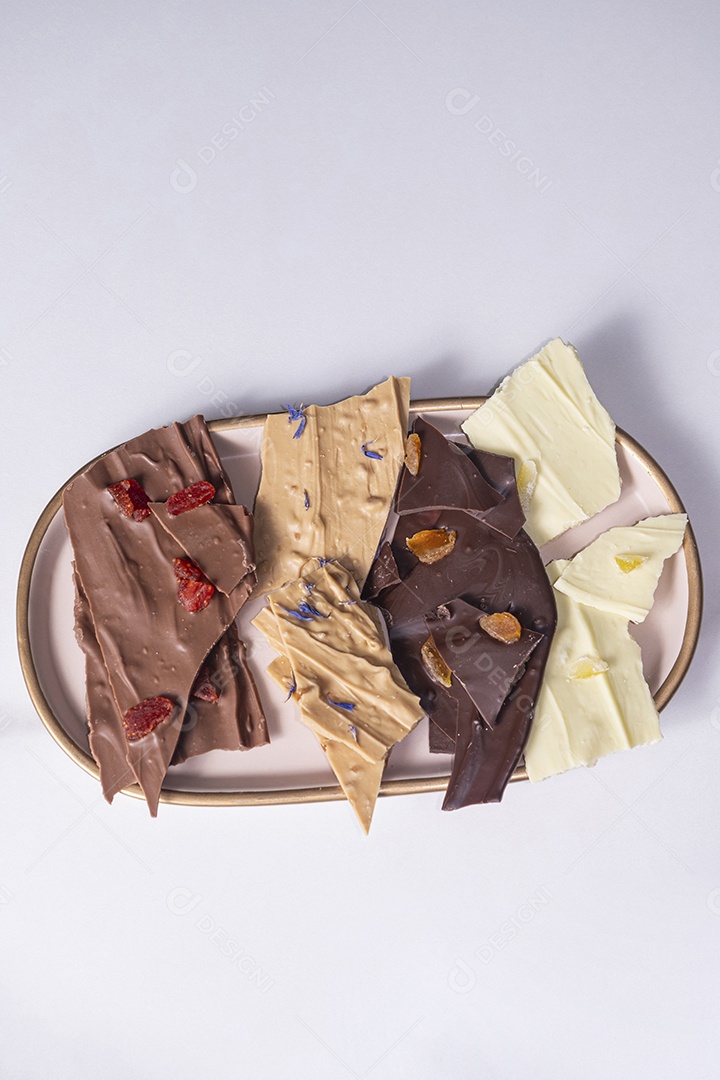 Uma caixa branca aberta com gotas de chocolate variadas