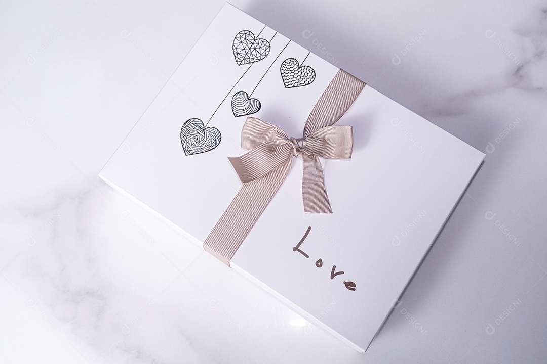 Uma caixa branca de chocolates decorada com corações um laço e a palavra amor