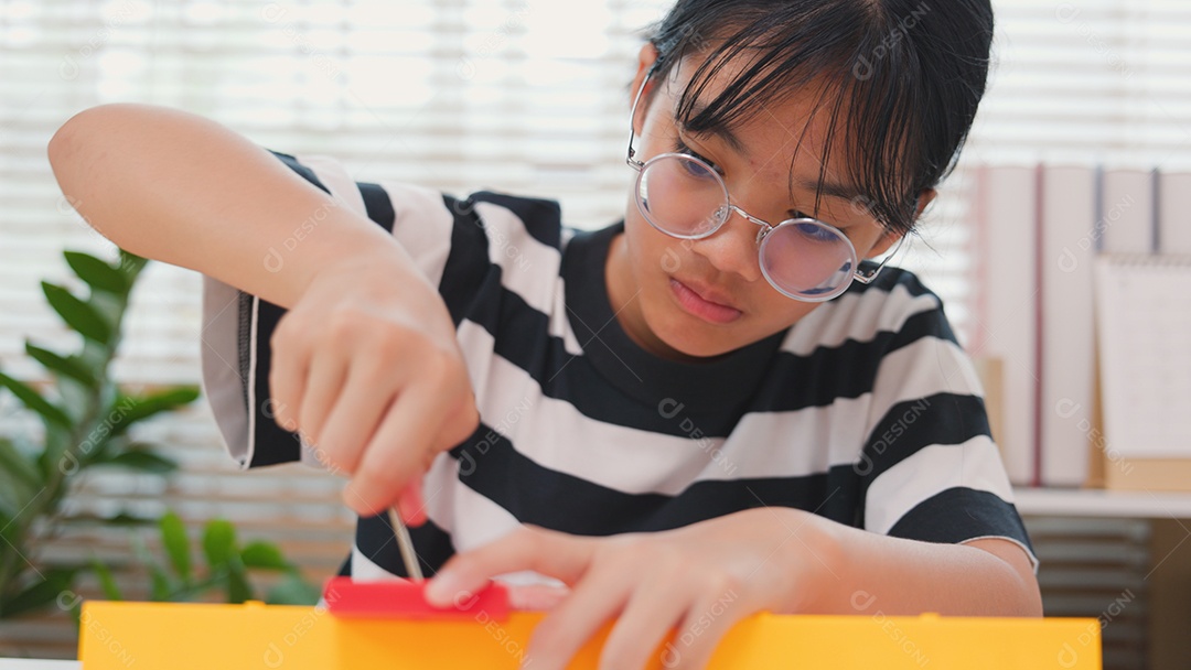 Menina asiática aprendendo STEM montando peças mecânicas com foco e determinação