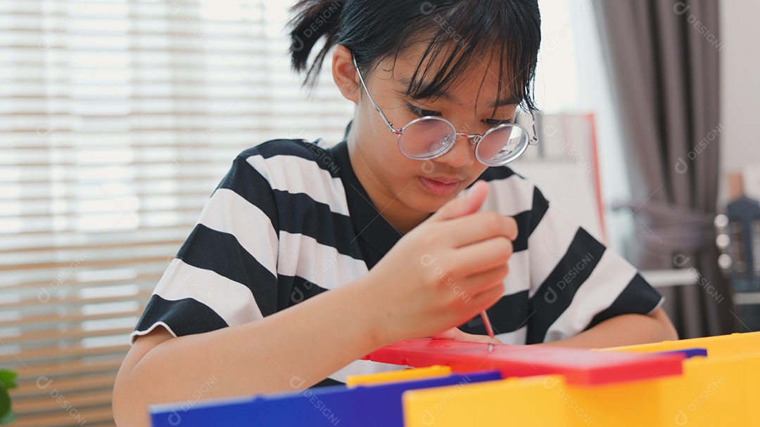 Menina asiática aprendendo STEM montando peças mecânicas com foco e determinação