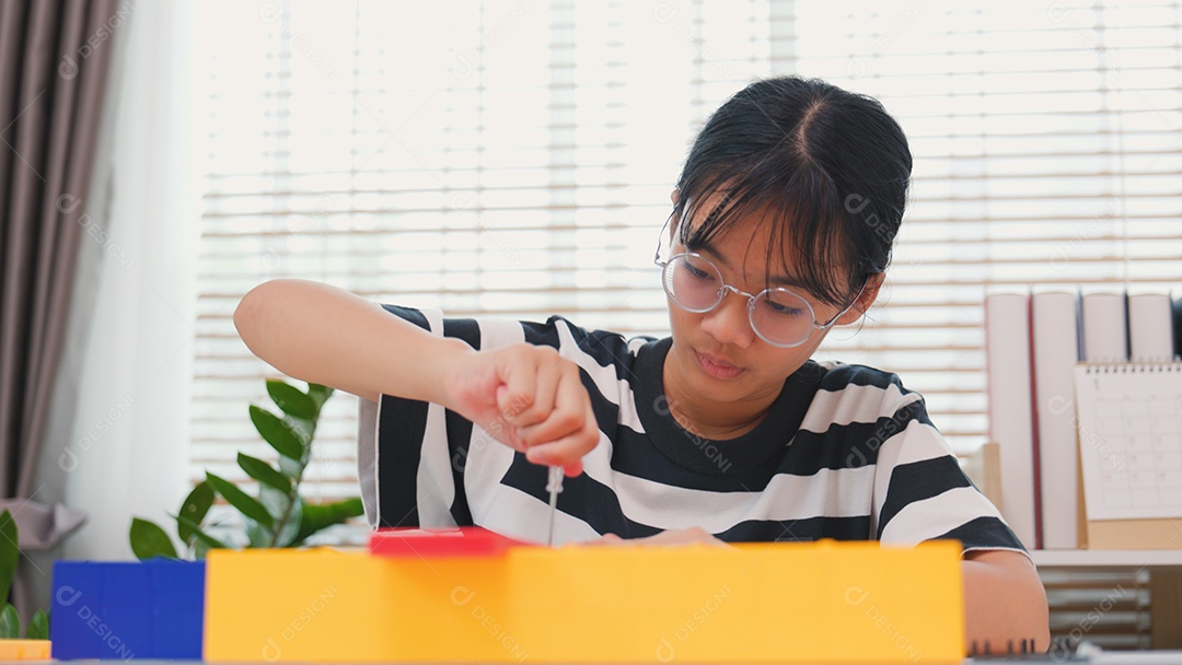 Menina asiática aprendendo STEM montando peças mecânicas com foco e determinação