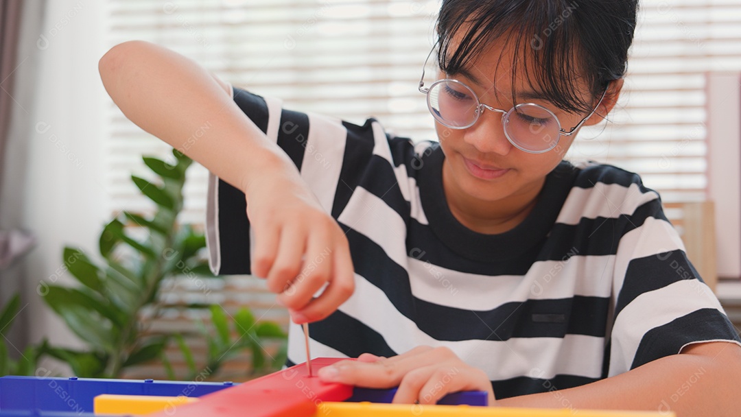 Menina asiática aprendendo STEM montando peças mecânicas com foco e determinação
