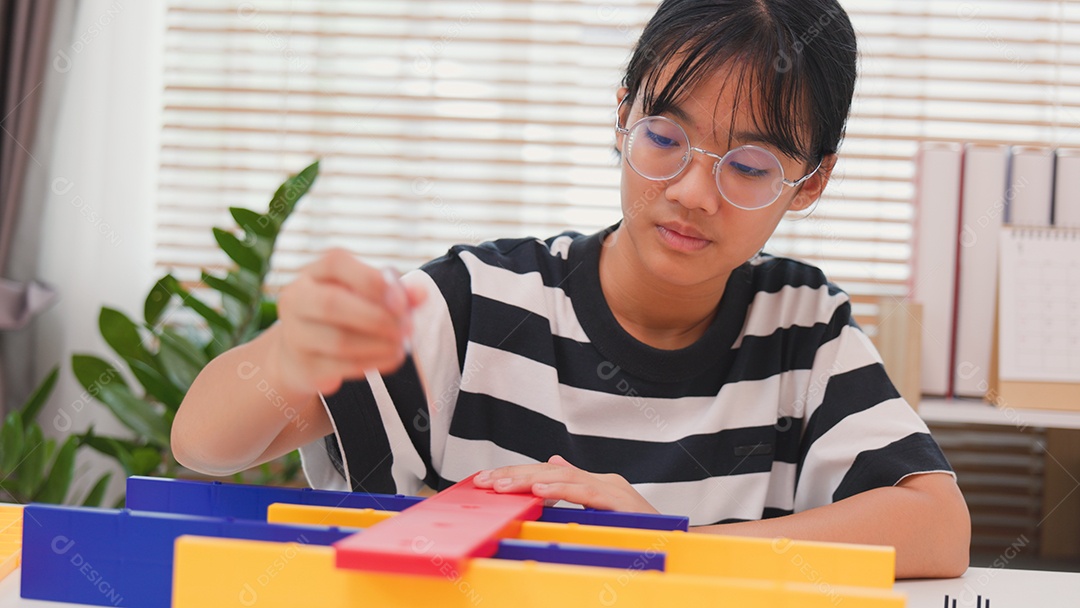 Menina asiática aprendendo STEM montando peças mecânicas com foco e determinação