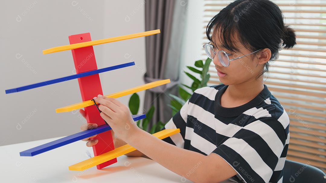 Menina asiática aprendendo STEM montando peças mecânicas com foco e determinação
