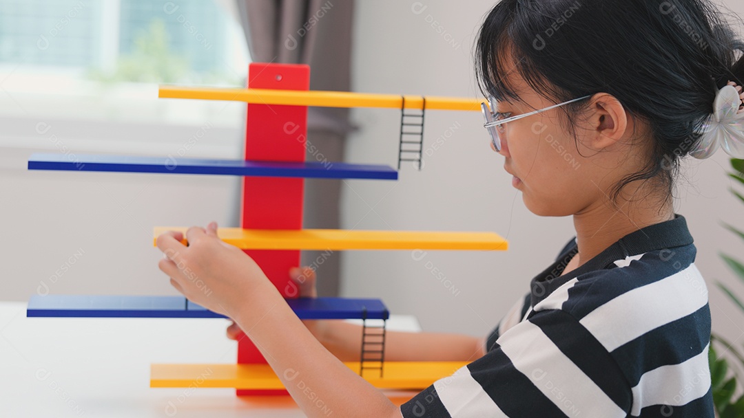 Menina asiática aprendendo STEM montando peças mecânicas com foco e determinação