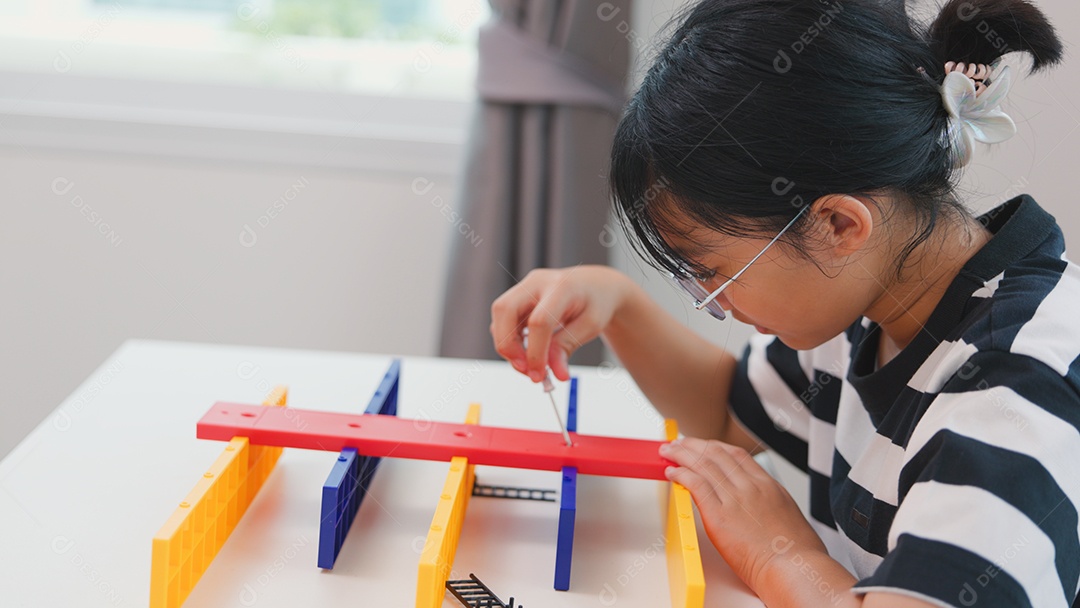 Menina asiática aprendendo STEM montando peças mecânicas com foco e determinação