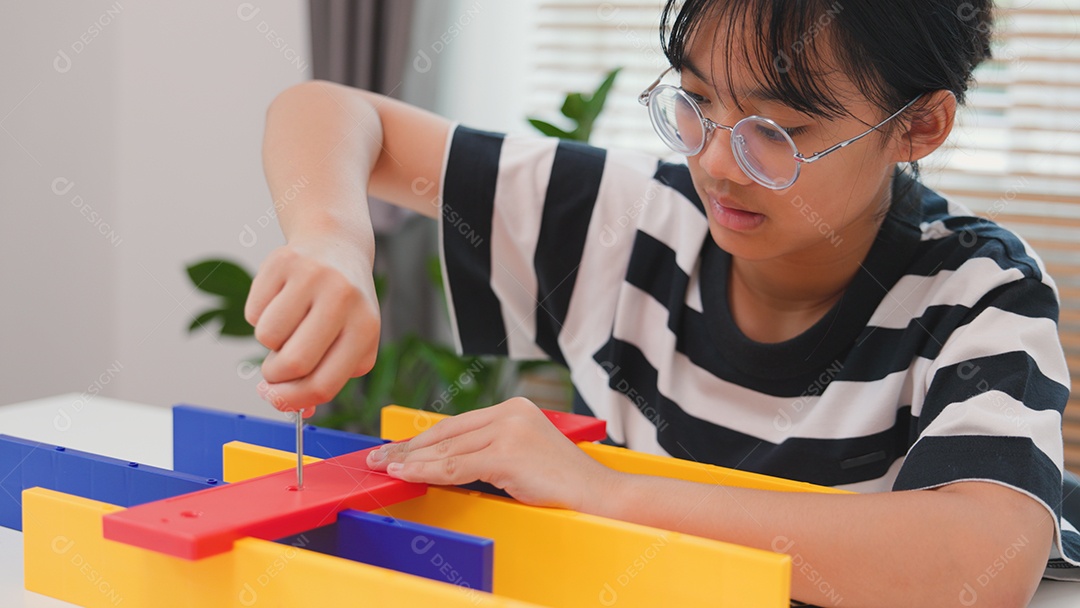 Menina asiática aprendendo STEM montando peças mecânicas com foco e determinação