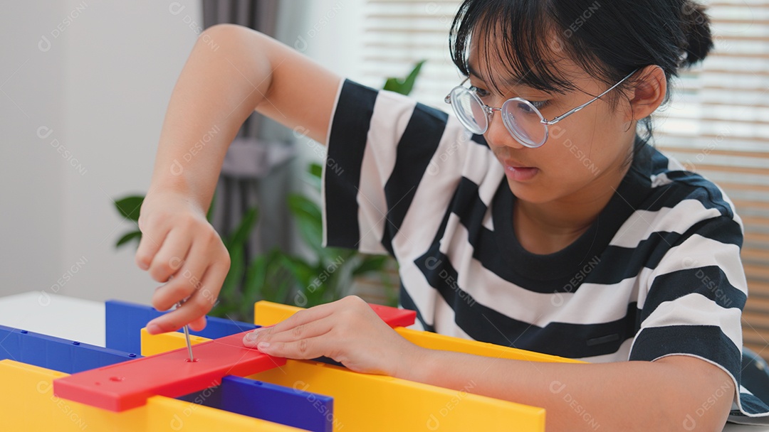 Menina asiática aprendendo STEM montando peças mecânicas com foco e determinação