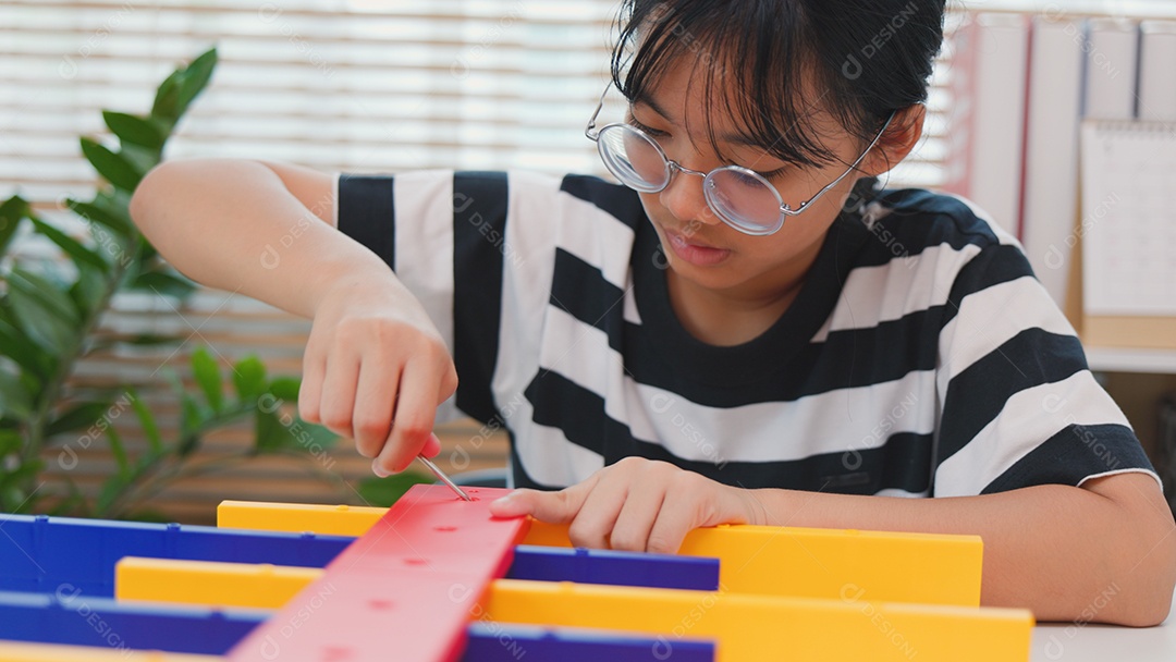 Menina asiática aprendendo STEM montando peças mecânicas com foco e determinação