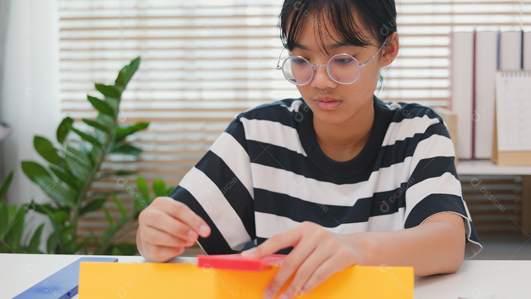 Menina asiática aprendendo STEM montando peças mecânicas com foco e determinação