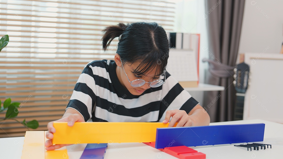 Menina asiática aprendendo STEM montando peças mecânicas com foco e determinação